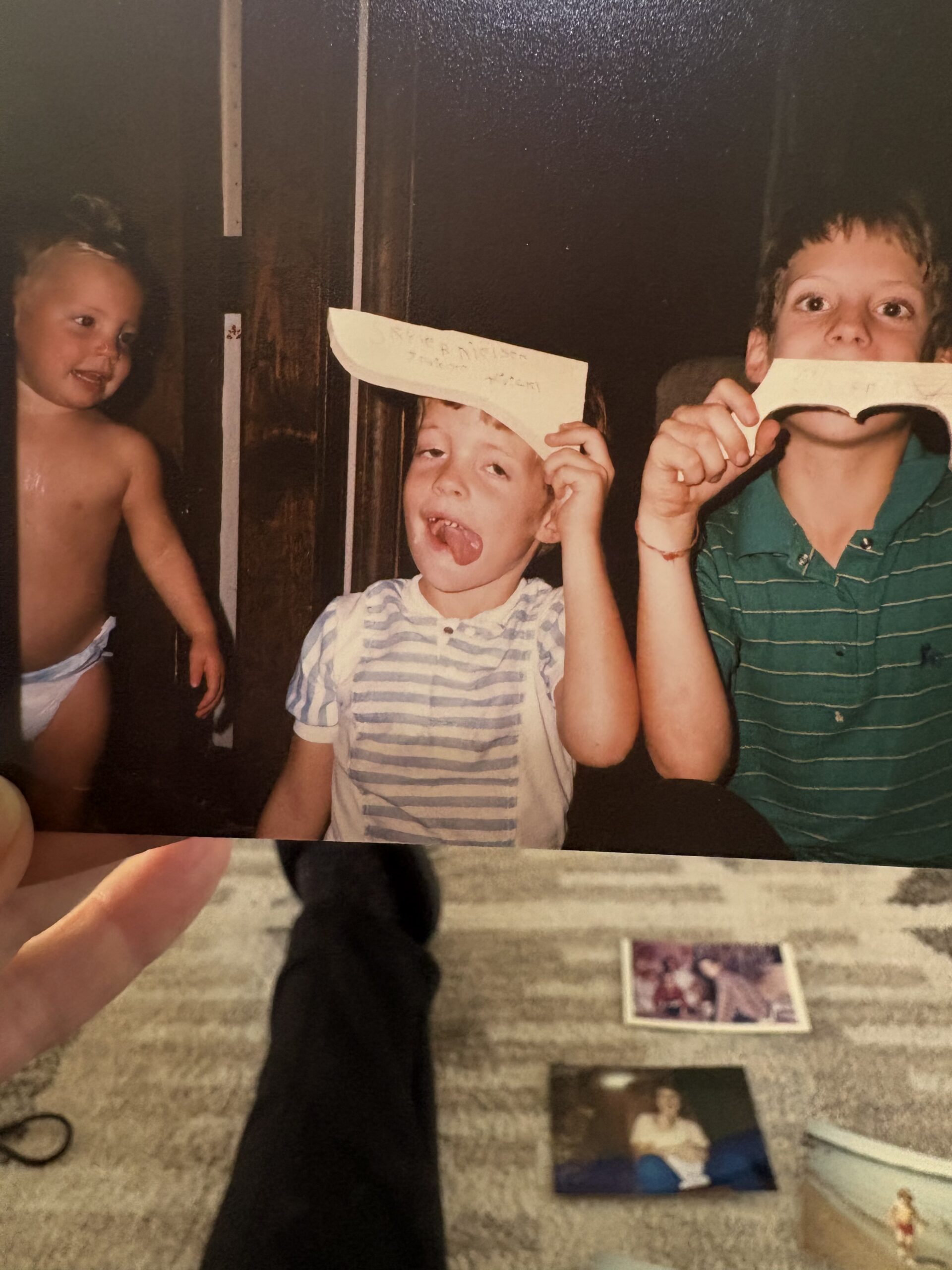A candid childhood photograph of three boys clowning around together